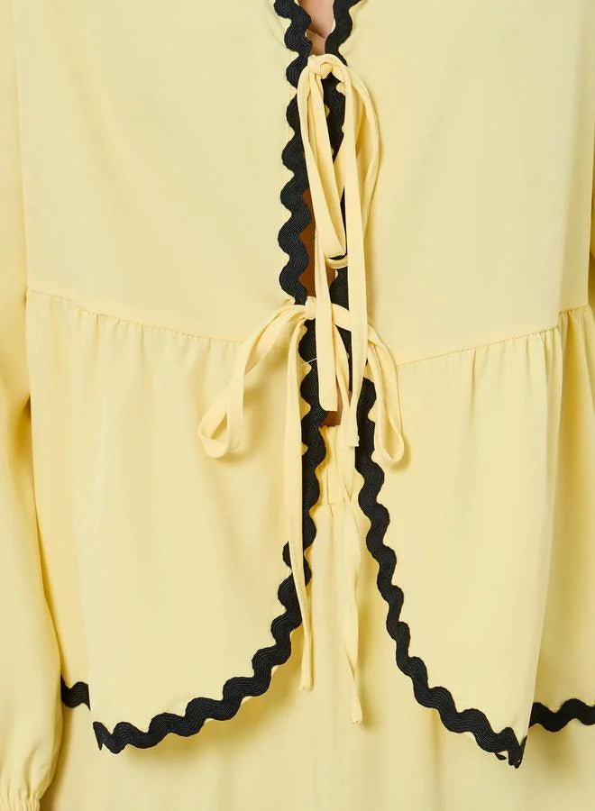 Ensemble composé d'un haut jaune à nouer orné de galons et d'une jupe longue à volants